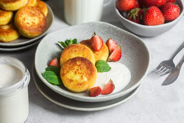 Syrniki Cheesecakes Appetizing cottage cheese pancakes with cream sauce, strawberries and mint in a...
