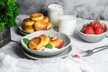 Syrniki Cheesecakes Appetizing cottage cheese pancakes with cream sauce, strawberries and mint in a...
