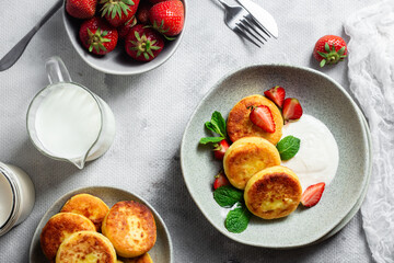Syrniki Cheesecakes Appetizing cottage cheese pancakes with cream sauce, strawberries and mint in a...