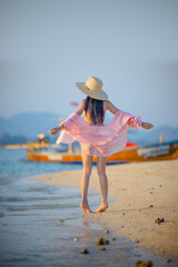 Woman in bikini standing relax posting at the edge of the sea beach, summertime traveling