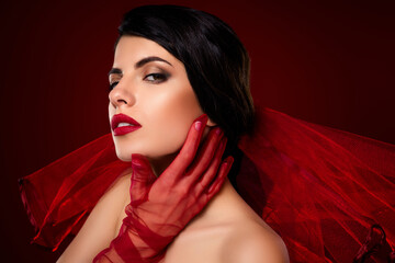 Elegant brunette woman showcasing fashionable style with red gloves and makeup against a rich...