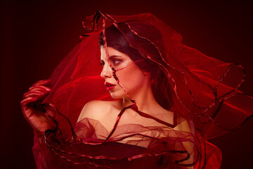 Elegant portrait of a woman wrapped in red veils, showcasing beauty, sensuality, and fashion allure