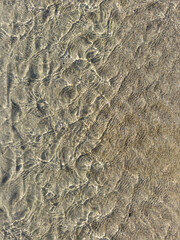 Reflections of light on the crystalline water and golden sand of the seabed