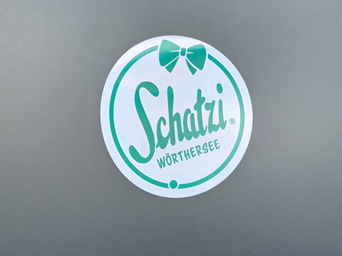 Schatzi w&ouml;rthersee logo on gray background with teal bow design