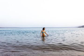 Slender girl in a swimsuit enjoys swimming in the sea. The girl relaxes and swims in the waters of the Red Sea in Israel.