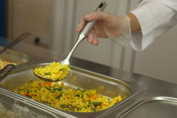School canteen worker at serving line, closeup. Tasty food