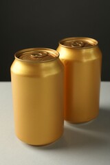 Two tin cans on white table against grey background, closeup