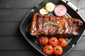 Delicious roasted pork ribs with rosemary, tomatoes and onions on grey wooden table, top view