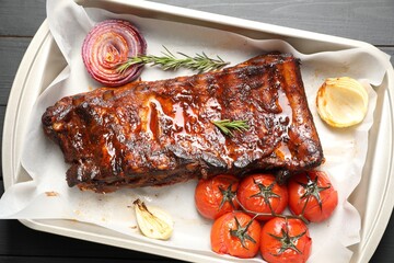 Delicious spare ribs, rosemary, baked onion and sun dried tomatoes on grey wooden table, top view