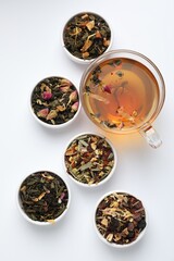 Delicious herbal tea and different brews on white background, flat lay