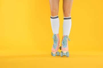 Woman in roller skates on orange background, closeup. Space for text