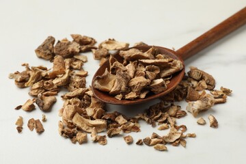 Pieces of dry chicory roots in spoon on white table, closeup