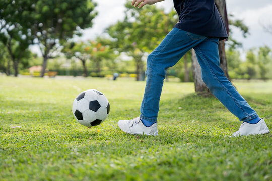 Little boy playing football in the garden with morning sunrise