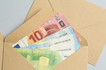 Money bonus. Envelopes with euro banknotes on light grey background, closeup