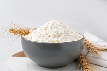 Wheat flour and spikes on white table, closeup