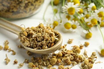 Dry and fresh chamomile flowers on light table, closeup