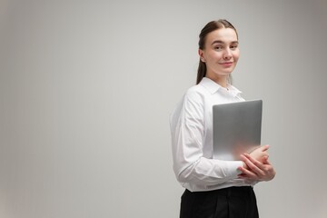Confident professional woman holding a laptop in a minimalist studio, ready for business...
