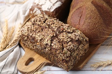 Fresh bread loaves and spikes on white wooden table, closeup