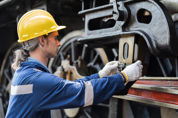 Locomotive repair garage, Mechanic, Engine Mechanic. Engineer checking, repairing, maintaining locomotive engine. Railway engineer and train wheel in train garage