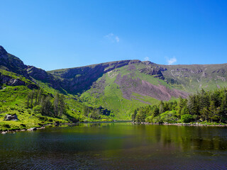 The green slopes of the mountain descend gently toward the still waters of the lake