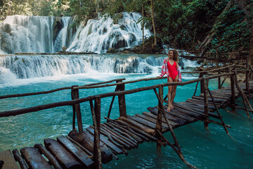Attractive woman on bridge at waterfalls with turquoise water in Central Sulawesi, Indonesia