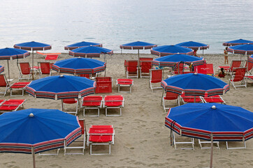 blue parasols and red sunbeds, in front of tre sea