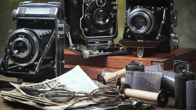 Old cameras in a composition on a wooden background, slowly moving in a horizontal plane.