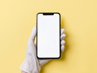 Hand in latex glove holding a blank screen smartphone. Shows hygiene and precautions. Yellow background gives a clean, modern aesthetic.