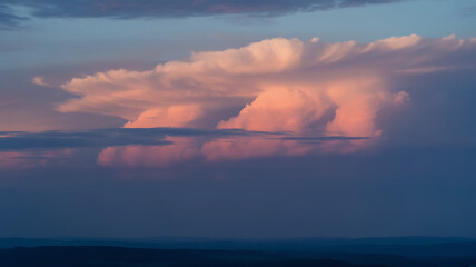 Pink sunset cloudscape over distant hills