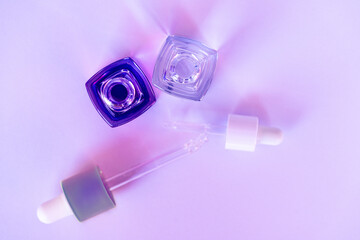 Two square glass dropper bottles with pipettes arranged on a pink background in soft lighting. Perfect concept for skincare, beauty, or cosmetic product branding.