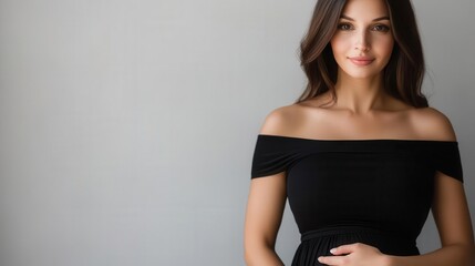 Fototapeta premium Studio portrait of a brunette expectant mother in a classic black dress