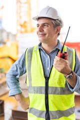 Foreman, supervisor, worker, loading master in works at construction site, control teamwork by walkie talkie radio for job done in the same direction, working at risk and high level of insurance.