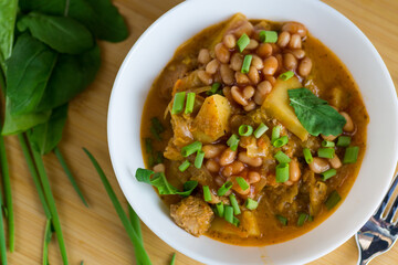Vegetable stew with meat and potatoes in a white bowl on the table