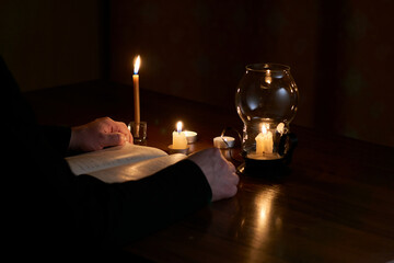 Man reads book by candlelight at home during power outage. Blackout. Power outage, energy crisis....