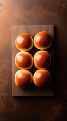 Fresh brioche buns arranged neatly on a wooden cutting board  