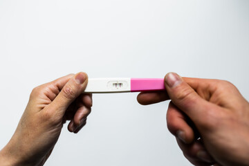 Couple holding positive pregnancy test together on white background. Lifestyle.
