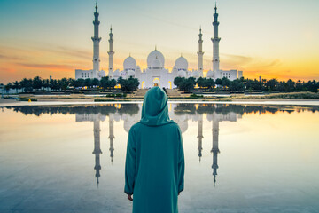 Close up Woman in traditional Arabic dress Abaya in Wahat Al Karama or Oasis of Dignity near Sheikh Zayed Grand Mosque in Abu Dhabi, showcasing cultural elegance,iconic Islamic architecture at sunset