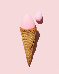 Pink beauty blender sponges coming out of ice cream cone on pink trendy background
