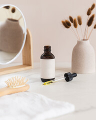 Glass amber dropper bottle on tan and marble trendy bathroom background 