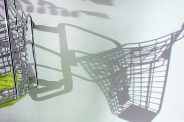 Shadow of a supermarket shopping cart on a white background with sunlight. Minimalist shopping concept.