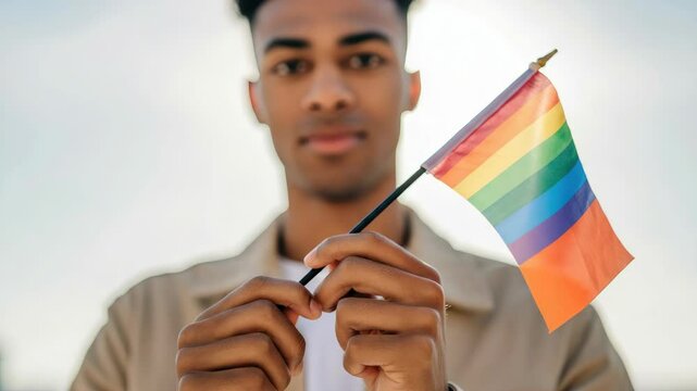 Young black male holding rainbow flag, symbolizing LGBTQ+ pride