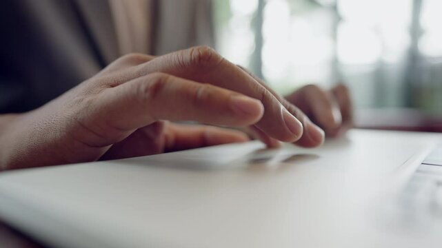 A person is typing on a laptop. The person is using the space bar. The laptop is on a table