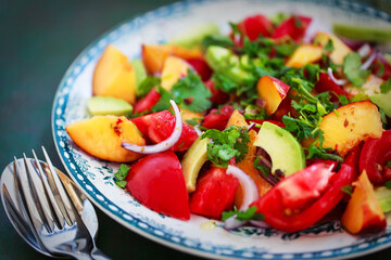 Fresh spring salad witn avocado, tomato, peach, red onion and herbs