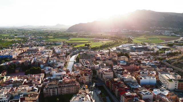 Drone point of view ancient spanish city of Orihuela, aerial shot of architecture and Segura River canal during sunny summer day. Costa Blanca, Alicante province. Spain