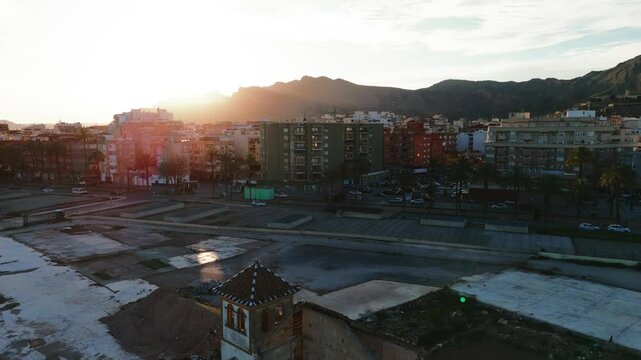 Aerial view of Orihuela townscape, urban with modern shopping mall, backdrop of mountains under bright blue sky. Spain, Costa Blanca