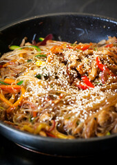 Asian glass noodle stir-fry with chicken and vegetables in a rustic ceramic  bowl