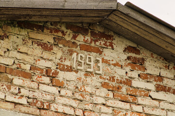 A brick building with the year "1993" engraved on it, featuring part of a wooden roof above, marking a past era in its construction	
