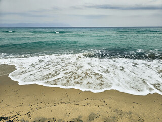 Calm sea waves gently lapping the shore on a cloudy day at the beach in Sarti on Sithonia peninsula, Greece