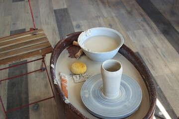Vase of raw clay on a pottery wheel in a workshop, modern equipment of a pottery studio, cloudy liquid in a large bowl, hobby of creative people, photo for advertising master classes