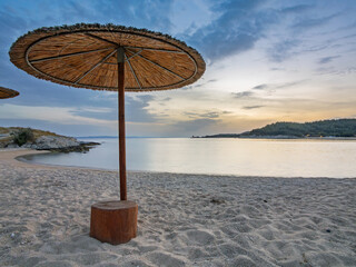 Serene beach with straw umbrellas at sunset in Toroni on Sithonia peninsula, Greece